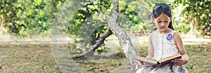 Banner Asian Girl holding book reading at green park in nature garden. Panorama Young todler girl relaxation read book. Happy