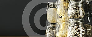 Banner with assortment of uncooked grains, cereals and pasta in glass jars on wooden table. Healthy cooking, clean eating, zero