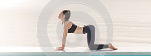 Banner of Athlete Attractive Asian woman relaxing in yoga Cat Cow Pose on the beach with beautiful sea