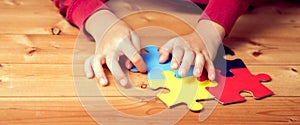 Banner, An autistic child`s hands play colorful jigsaw puzzle symbol of public awareness for autism spectrum disorder. World