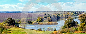 Banner. Autumn landscape with river, trees and plowed field on a sunny day. Wide panorama of autumn nature