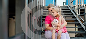 Banner blonde little girl with cochlear implant playing with her mother outdoor. Hear impairment deaf and health concept