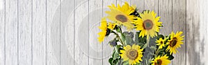 banner of A bunch of sunflowers in a black vase on a rustic white wooden table