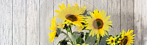 banner of A bunch of sunflowers in a black vase on a rustic white wooden table