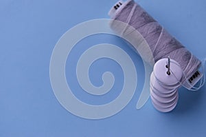 Banner button needle and gray thread on a blue background view from above with copy space