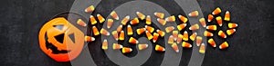 Banner Candy corn candies spilled out of the pumpkin basket. Traditional sweets on Halloween. Treat or trick