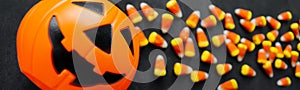 Banner Candy corn candies spilled out of the pumpkin basket. Traditional sweets on Halloween. Treat or trick