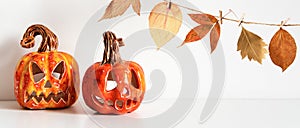 Banner with Ceramic Jack Lanterns and autumn leaves garland on table wall background