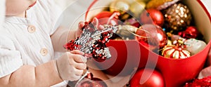 Banner Close-up Christmas Baby in Santa Hat, Child holding christmas bauble near Present Gift Box over Holiday Lights