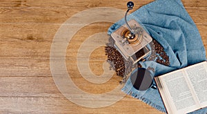 Banner with coffee beans, antique coffee grinder, coffee cup and a book on a blue fabric. Wooden background