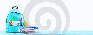 Banner. Concept back to school. Full turquoise School Backpack with stationery on table