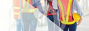 Banner with copy space of male and female Engineer holding safety helmet, standing in outdoor civil project construction site.