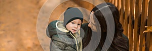 Banner cute little asian boy stands with mother outdoors copy space. Happy child walking in autumn park. Toddler baby