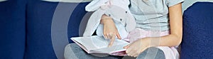 Banner Cute little girl eading a book with stuffed teddy bunny toy