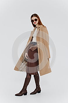 Banner for the design of the showroom clothing brand. Stylish redhead lady in beige coat glasses posing on a white