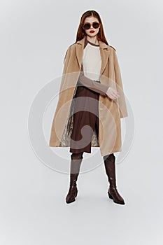 Banner for the design of the showroom clothing brand. Stylish redhead lady in beige coat glasses posing on a white