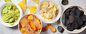 Banner of different types of colored potato chips in white bowls, gray background. Fast food concept