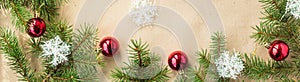 Banner of Festive christmas border with red balls on fir branches and snowflakes on rustic beige background