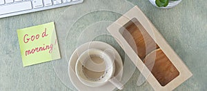 banner with flat lay with of the desktop. note with the words GOOD MORNING, pancakes in paper box, cup of coffee