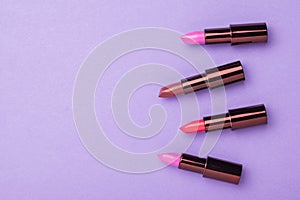 A banner with four tubes of lipstick on a purple background. Space for the text. Flat lay