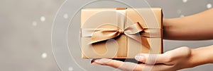 Banner with gift box in woman hands. Copy space, blurred background. Useful for greeting card. Concept Happy