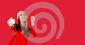 Banner. Girl holds a gift box and points up with a finger. Red background with space for your advertisment.