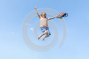 Banner with Girl in a jump against the blue sky with a school bag. Happy summer