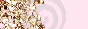 Banner with gold colored hearts confetti on a pink background.