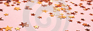 Banner with gold colored stars confetti on a pink background.