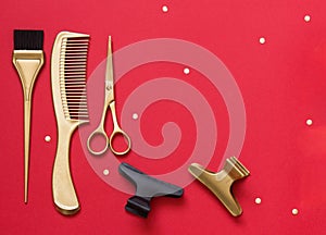 Banner with hairdressing tools on a red background. Gold scissors, comb, coloring brush and hair clips. Template for a