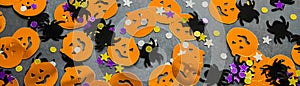 Banner with Halloween background: shiny confetti in the shape of orange pumpkins, black spiders and purple, golden stars