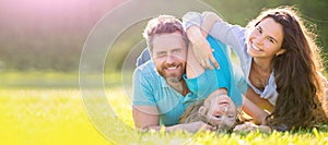 Banner of Happy family Lying on grass. Young mother and father with child son in the park resting together on the green