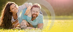 Banner of Happy family Lying on grass. Young mother and father with child son in the park resting together on the green