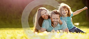 Banner of Happy family Lying on grass. Young mother and father with child son play in the park resting together on the