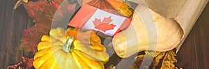 Banner. Happy Thanksgiving Day in Canada. Vegetables, pumpkins, squash, apples, maple and oak leaves, acorns on a wooden backgroun