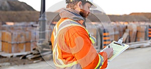 Banner of inspector in orange workwear with blueprints on construction site.