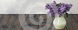 banner with lilac branches in a clay vase on a wooden background. Beautiful lilac flowers. Spring blossom. spring or