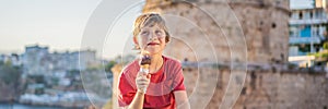 BANNER, LONG FORMAT Boy tourist eating turkish ice cream on background of Hidirlik Tower in Antalya against the backdrop photo