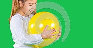 Banner- long format. Closeup photo of little girl, trying to bite a iluminating color balloon on a green background