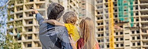 BANNER, LONG FORMAT Family mother, father and son looking at their new house under construction, planning future and