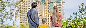 BANNER, LONG FORMAT Family mother, father and son looking at their new house under construction, planning future and