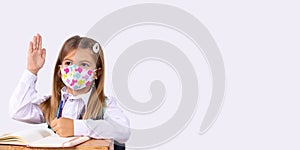 Banner, long format. A junior class girl in a school uniform and wearing a mask sitting at her desk. A new concept for