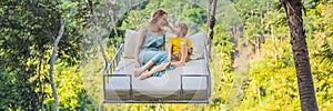 BANNER, LONG FORMAT Mother and son swinging in the jungle rainforest of Bali island, Indonesia. Swing in the tropics