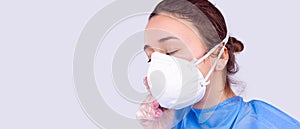 Banner,long format. A young girl doctor, tired after a hard day at work, takes off her protective respiratory mask