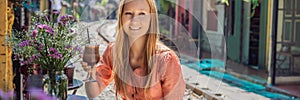 BANNER, LONG FORMAT Young woman traveler drinks coffee sitting by the railway paths which go through residential area in