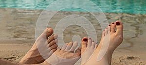banner with male and female feet lie on the sand against the background of blue water. two pairs of legs. concept of