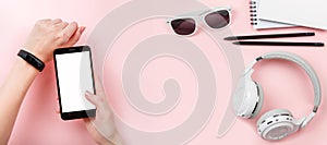 Banner mock up phone in hands with Fitness tracker, headphones, glasses on pink background.