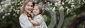 Banner mom and little daughter in the apple orchard