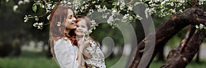 Banner mom and little daughter in the apple orchard