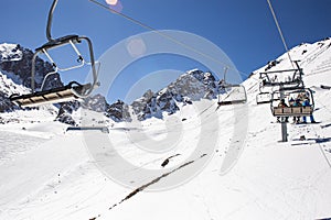 Banner panorama of ski resort, skiers on the ski lift, white snow pine trees at pink sunset or dawn